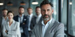 © Surachetsh - An authoritative business leader stands with team in sleek office setting, ready to drive company forward, essence of experienced, emphasizing readiness for modern business challenges.