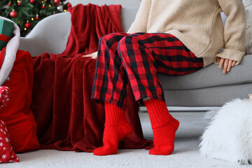 Wall Mural - Woman in warm red socks sitting at home on Christmas eve