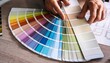 © ImagePulse - A close-up view of hands selecting color swatches from a fan deck, emphasizing creativity and choice in design.