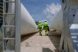 © Nassorn - Maintenance engineer team standing at windmills at wind turbine farm. Group of people wear safety helmet and uniform working at alternative renewable energy wind station. Sustainable energy technology