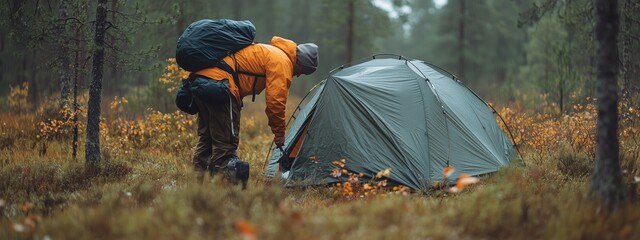 Canvas Print - Camping enthusiast sets up a tent in the tranquil forest during autumn, surrounded by colorful foliage and soft morning light