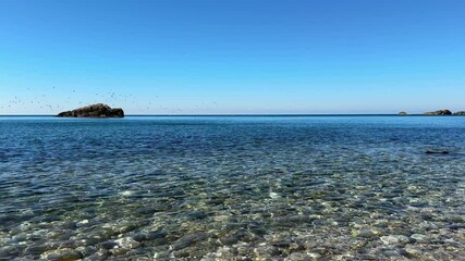 Canvas Print - Sea, sky, pebbly beach and rocks on horizon.