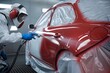 © Nida - Painter sprays red paint on cars door, protective sheet covers, precise detail shown