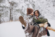 © anatoliycherkas - Cute young couple in love with pine bouquet spending time on Valentine's day in snowy winter forest in mountains