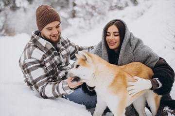 Wall Mural - Happy young couple with akita dog in forest on winter day