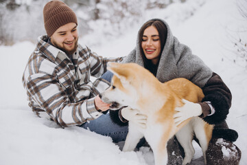 Wall Mural - Happy young couple with akita dog in forest on winter day