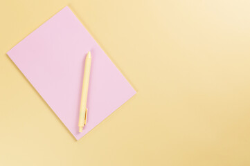 Wall Mural - Top view of pink notebook, yellow pen on yellow background. School, office wallpaper. Flat lay, copy space.