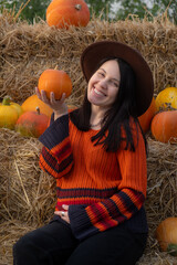 Wall Mural - Woman holding a pumpkin sitting on hay bales