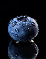 Close-up of fresh blueberry with water droplets on a solid black background