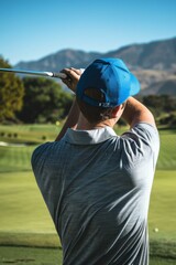 Poster - A man in a blue hat swinging his golf club on the green. AI.