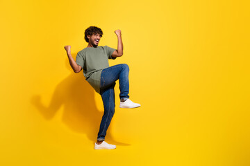 Poster - Full size photo of ecstatic guy dressed khaki t-shirt jeans scream yeah raising fists up win bet isolated on yellow color background