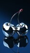 © RaptorWoman - Two metallic cherries connected by stems on a reflective surface, highlighting modern design and artistic aesthetics.