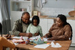 © Seventyfour - Family enjoying quality time together sitting at table doing arts and crafts activity Parents and children collaborating and creating colorful art pieces