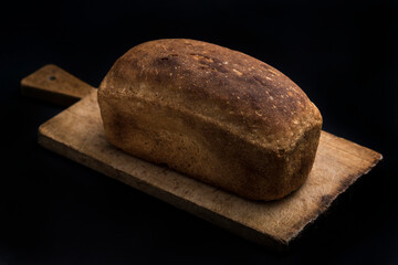 Brown bread on a wooden desk on dark background.