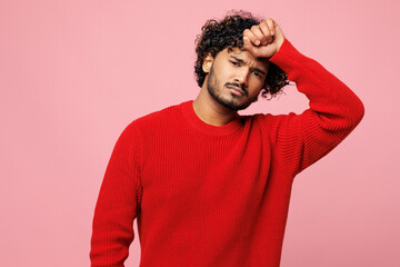 Wall Mural - Young sad sick ill Indian man wear red sweater casual clothes put hand on forehead look camera suffer from headache isolated on plain pastel light pink background studio portrait. Lifestyle concept