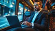 © Galib - A businessman in a suit working on a laptop while riding a bus.