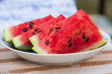 Red watermelon is cut into slices on a plate