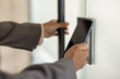 © Tetiana - Close-up photo of the hands of a young African-American woman in a suit opening an office door by scanning a mobile phone