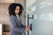 © Tetiana - Young african american business woman enters office through electronic key, puts mobile phone to scan glass door lock