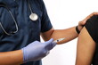 © ArvStd - Close-up of medical nurse being vaccinated in studio by doctor. Medic uses syringe with needle to administer vaccination injection to arm of asian healthcare specialist.