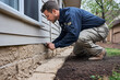 © dK - Man inspecting and repairing home foundation cracks near the exterior wall to prevent structural damage