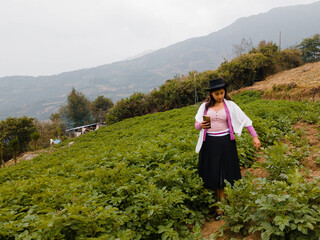  Foto de una feliz y bonita campesina con un sombrero hablando por un teléfono celular en los Andes peruanos. Mujer usando teléfono móvil