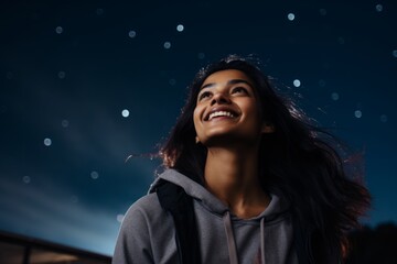 Poster - Portrait of a joyful indian woman in her 20s showing off a lightweight base layer over sparkling night sky