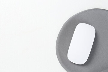 Mouse and mousepad on white table, top view. Space for text