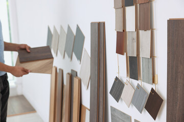 Sticker - Man with different samples of wooden flooring indoors, closeup