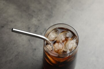 Tasty refreshing drink with straw in glass on grey table, closeup