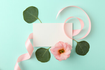 Canvas Print - Blank card, flower, leaves and ribbon on turquoise background, flat lay