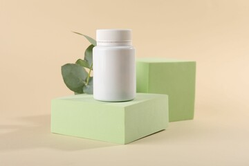 Canvas Print - Plastic medical bottle, eucalyptus leaves and podiums on beige background