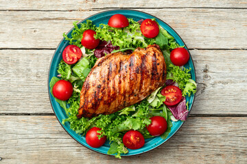 Grilled chicken breast ( fillet ) with lattuce salad and cherry tomatoes . Top view