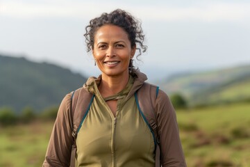 Poster - Portrait of a content indian woman in her 50s sporting a breathable hiking shirt isolated in quiet countryside landscape