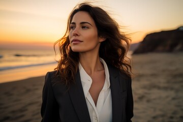 Canvas Print - Portrait of a blissful woman in her 30s dressed in a stylish blazer while standing against beautiful beach sunset