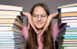 © Iryna - Thoughtful student surrounded by tall stacks of books. A young student with glasses sits at a desk surrounded by large stacks of books.