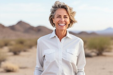 Sticker - Portrait of a joyful woman in her 50s wearing a simple cotton shirt isolated in backdrop of desert dunes