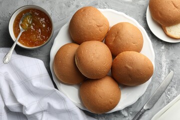 Wall Mural - Fresh tasty buns and jam on grey table, top view