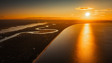 Wall Mural - the sun sets over a body of water, featuring a surfboard in the foreground