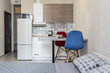 © Diana - design of a small modest apartment. Cozy kitchen, red and blue chair, refrigerator. A large bed with pillows.