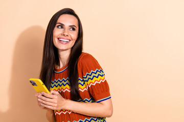 Poster - Portrait of pretty young lady hold phone look empty space wear t-shirt isolated on beige color background