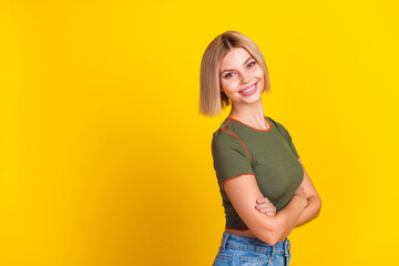 Wall Mural - Photo of adorable girl with bob hair dressed khaki t-shirt arms folded stand near promo empty space isolated on yellow color background