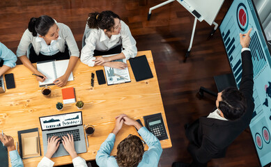 Wide top view of diverse group of business analyst team analyzing financial data report paper on meeting table. Chart and graph dashboard by business intelligence analysis. Meticulous