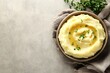 © Wish Craft Arts - Bowl of creamy mashed potatoes with butter and herbs on a grey background.