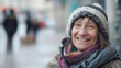 © Bonsales - Smiling homeless woman wearing a fuzzy beanie and layered scarves standing outdoors. Blurred street background with people and buildings