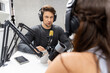 © InfiniteFlow - Host channel broadcaster with special guest making advice for problem in live streaming with listeners surrounded sets of live streaming on radio talking show at comfy modern workplace. Postulate.