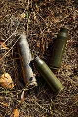 Brass case of damaged ammunition from a fired military firearm, weapon element in dry grass in the middle of the forest. Close-up color vertical photo.