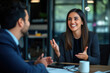 © Danny - Young woman smiles and gestures as she engages in a lively conversation with a colleague during a business meeting. Professional communication, teamwork, business collaboration.