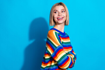 Sticker - Photo of attractive young woman crossed arms turn around look empty space dressed stylish striped clothes isolated on blue color background