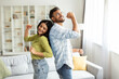 © Home-stock - Joyful indian couple dancing in living room interior, having fun and singing, husband and wife enjoying spending time together